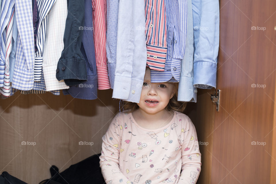 Girl of 4 years is crying in the wardrobe of her father.