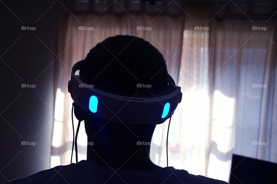 A young man engages in a session of virtual reality gaming in the living room of his home.