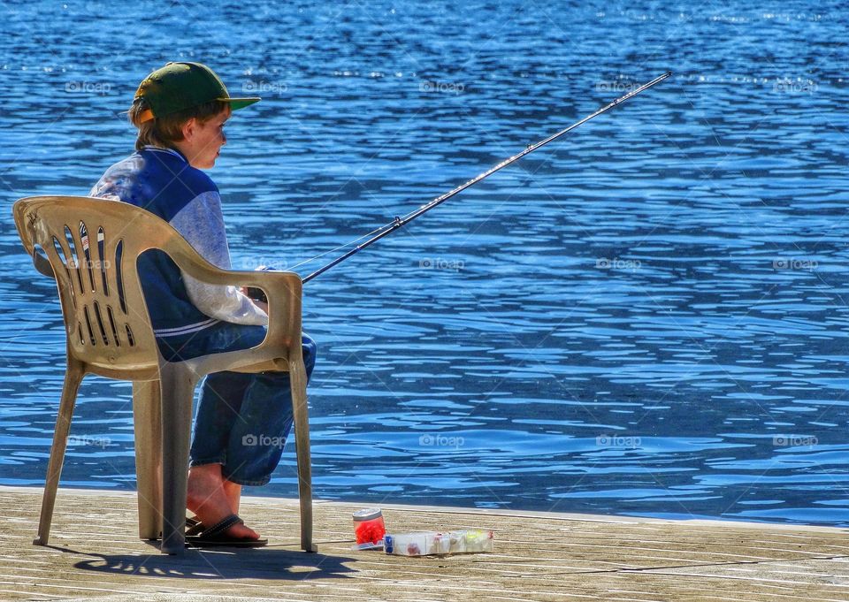 Boy Fishing From A Pier In Summer