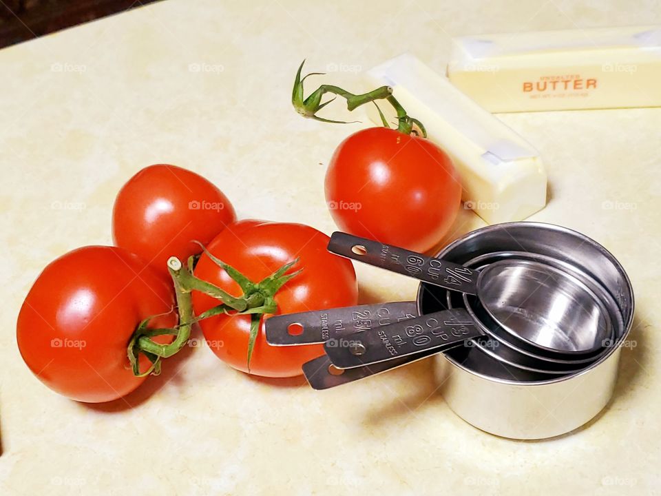 vine ripe tomatoes and stainless steel measuring cups on a counter top with butter