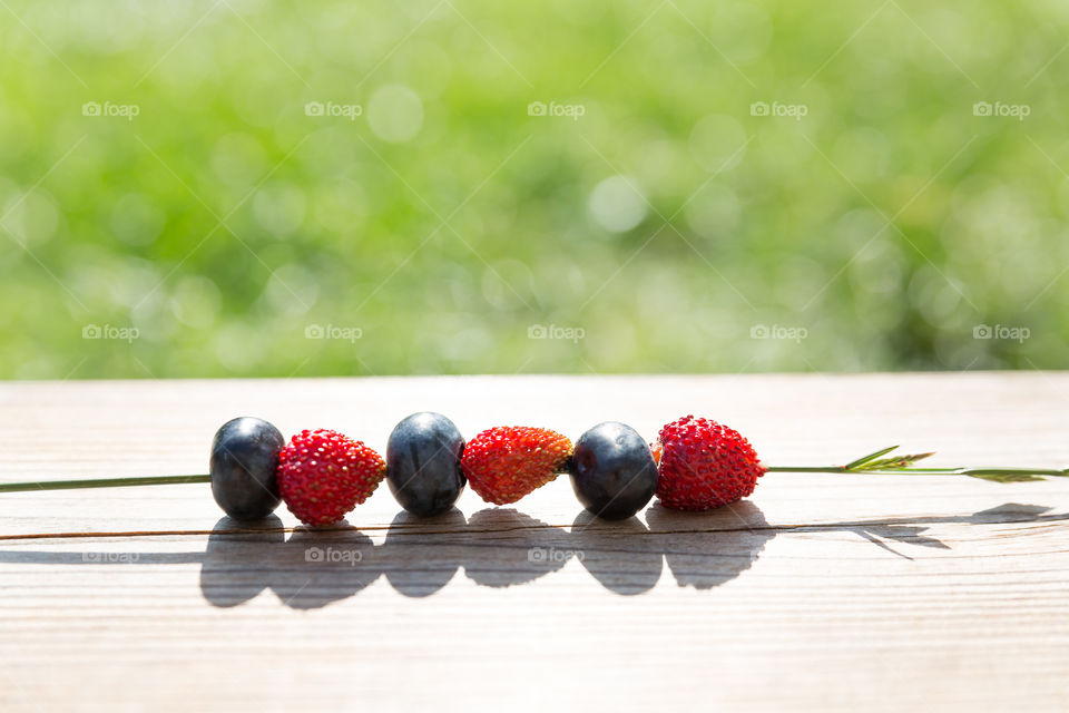 Blueberries and strawberries on a grass straw in bright sunshine 
