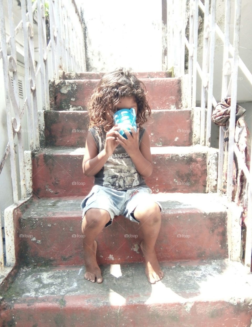 Photographs of a child/photo of a child climbing on a ladder/a photo of an Indian boy/a photo of a child wearing a hat/a photo of a little boy above/a photo of a poor little boy/a unique photo of a child climbing an iron ladder  Photo/real & natural