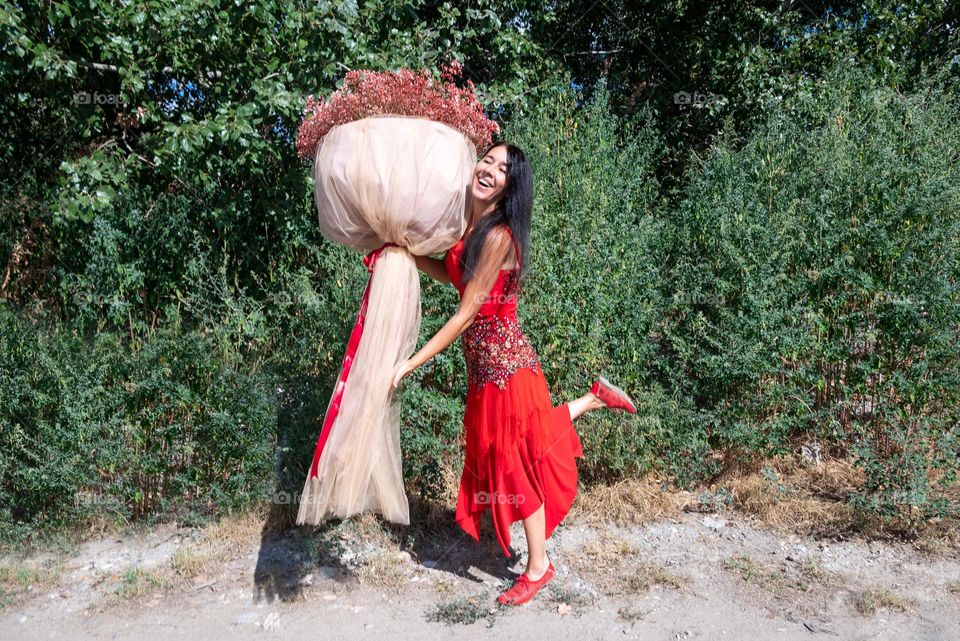 Woman Dances with a Large Bouquet of Red Flowers