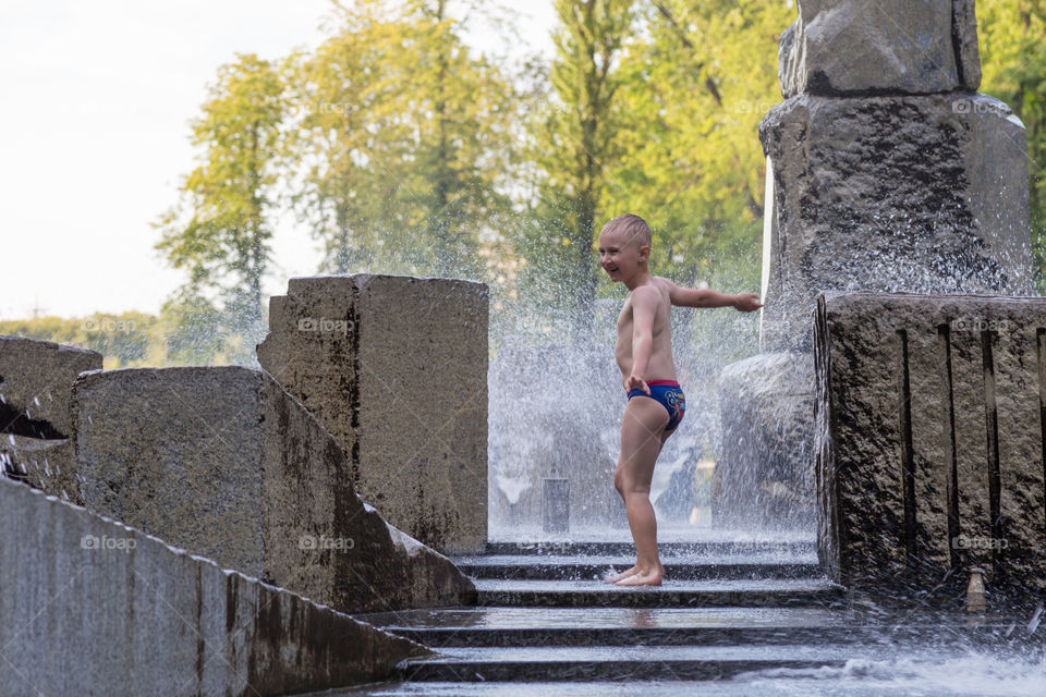 A boy is playing in a fountain