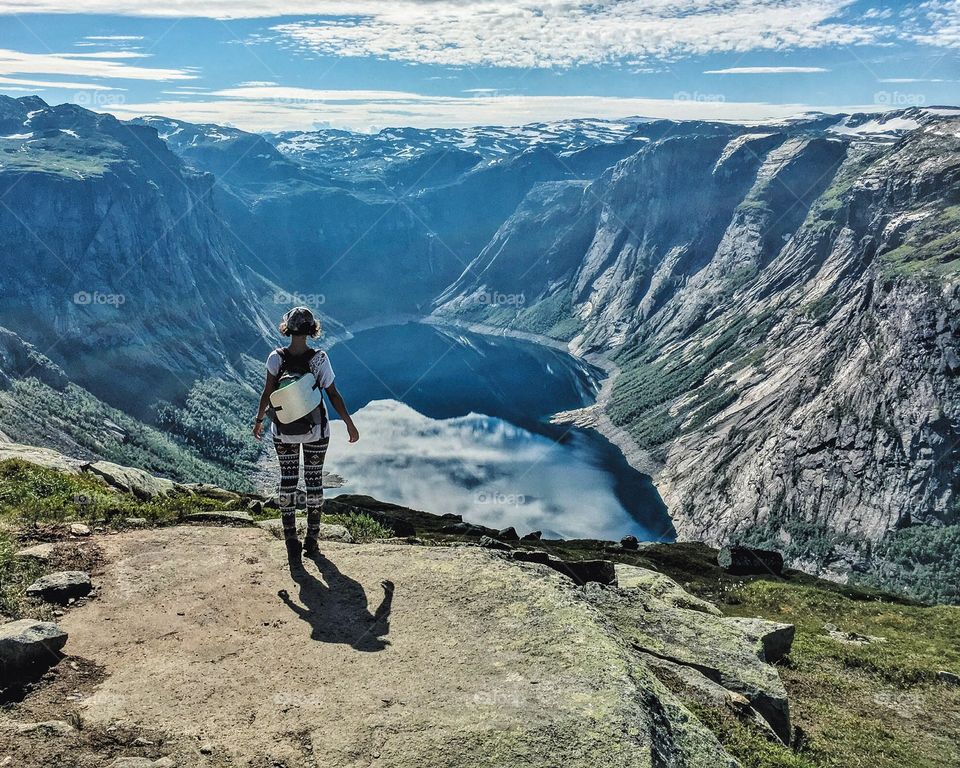 A girl standing above the lake while hiking in Norwegian mountains. 