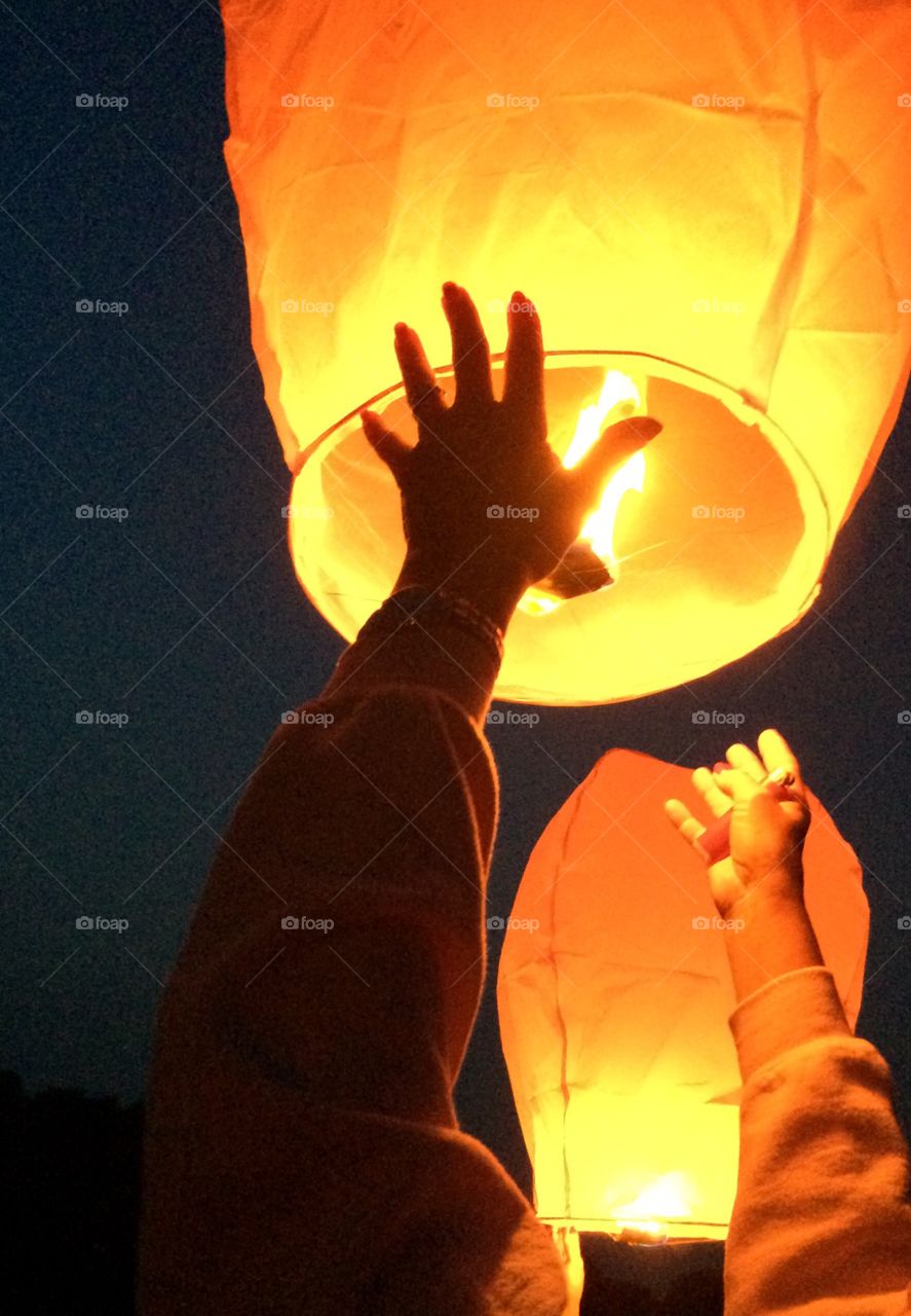 Wishing lanterns being lit and sent into the air. 