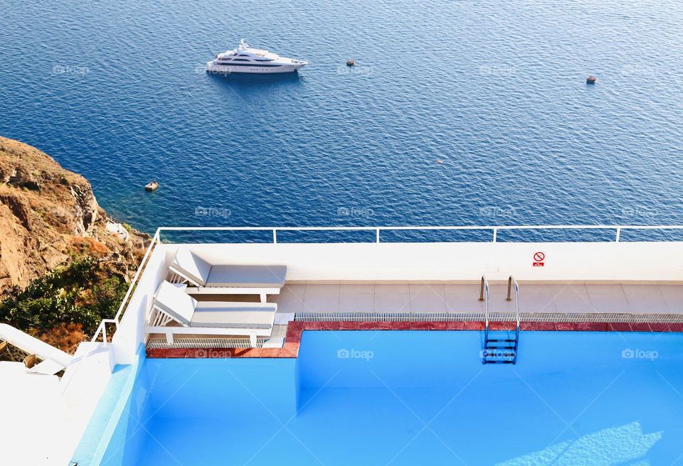 Pool with bright blue water in the foreground and the Mediterranean Sea and a cruiser in the background 