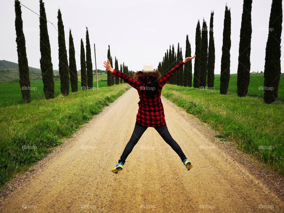 Girl jumps along a tree lined avenue