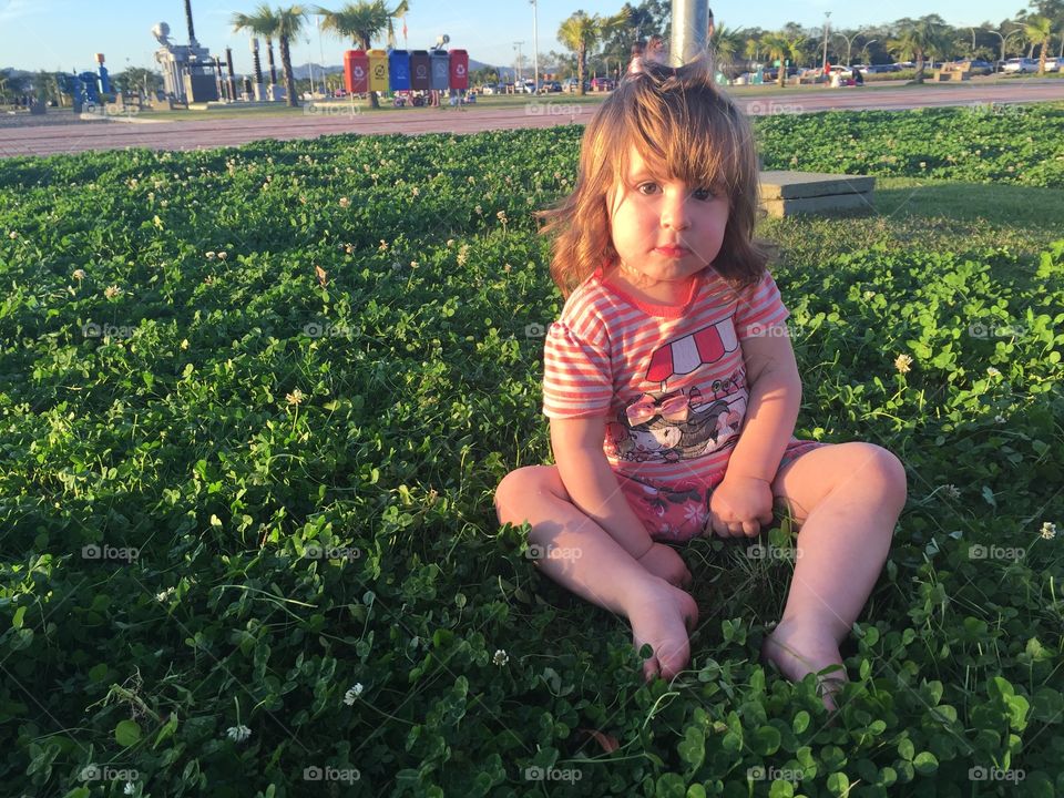 Innocent baby girl sitting on grass