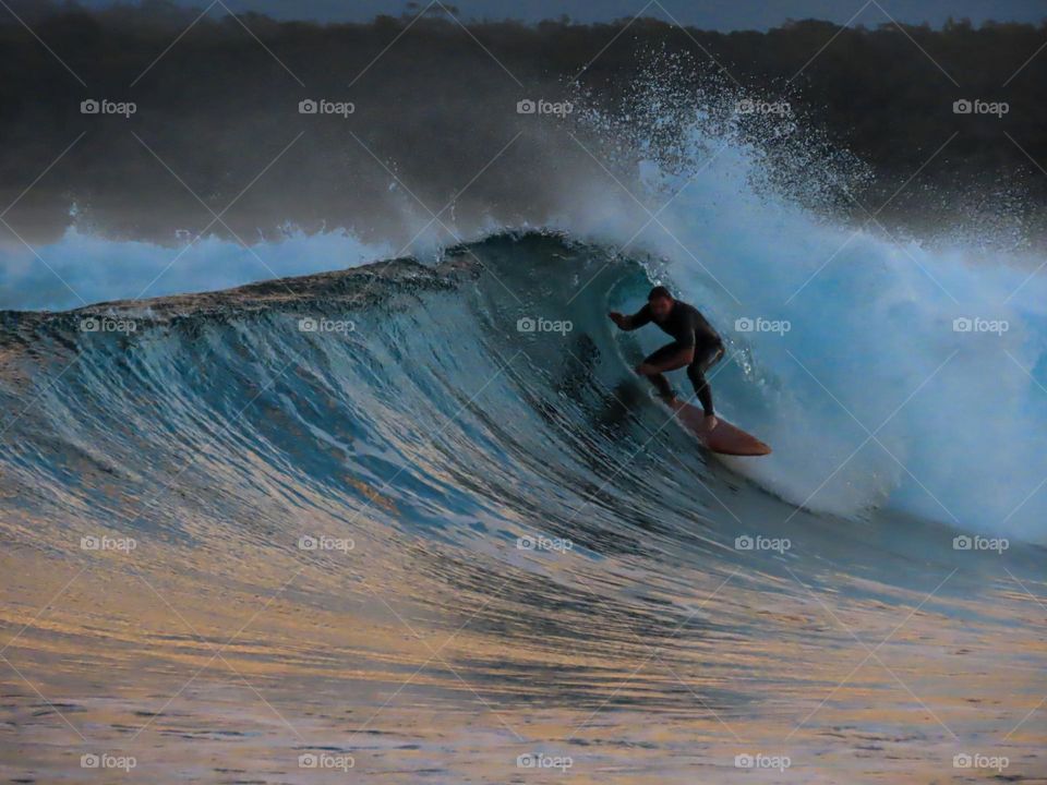 Surfer surfing a barrel wave at sunset 