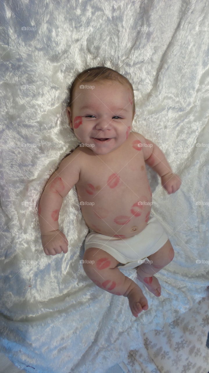A baby boy 3 months old covered in red lipstick kisses