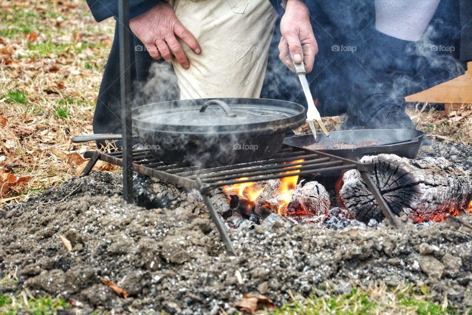 Unrecognizable man stands behind a barbecue with flames and smoke