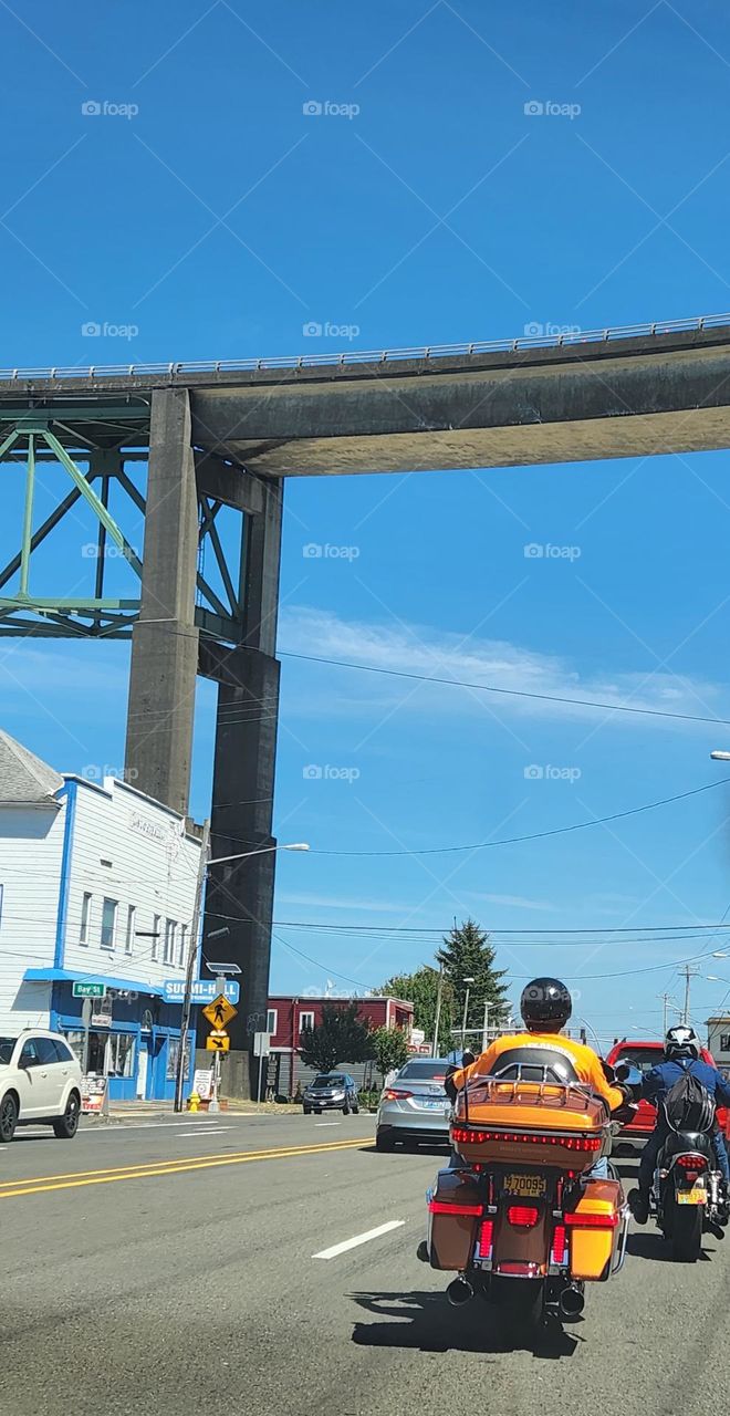 people riding motorcycles under a bridge through Astoria Oregon traffic in Summer