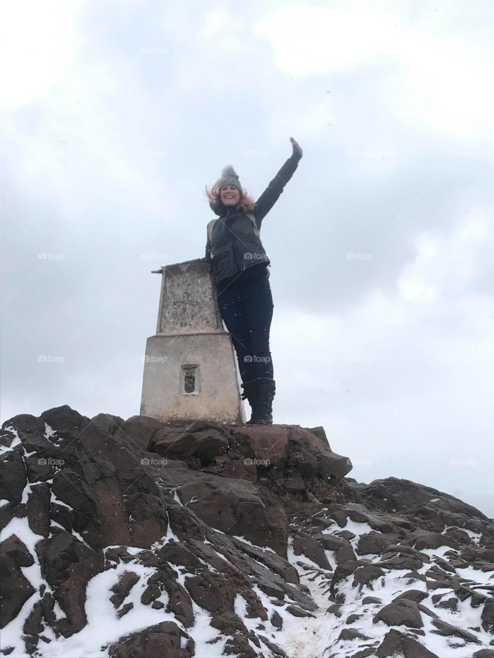 woman on top of mountain in snow celebrating
