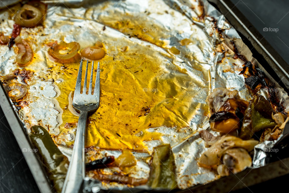 baking tin on it foil, fat, dirty fork and leftovers after roasting