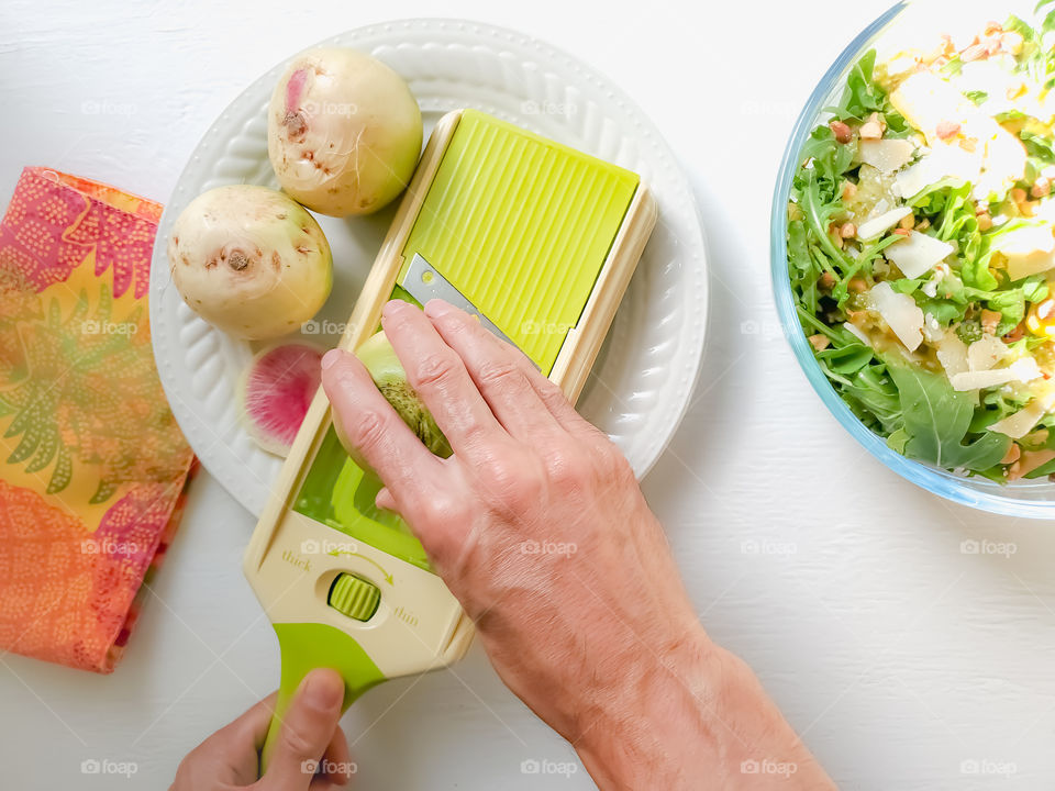 Slicing watermelon radishes for a salad with a mandolin.