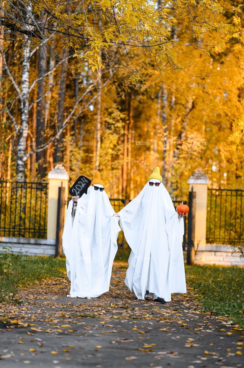 People in ghost costumes and knitted hats. Halloween mood. Autumn season