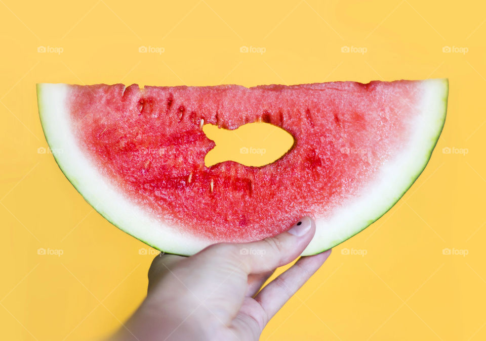 Fish shape hole in a watermelon slice in hand