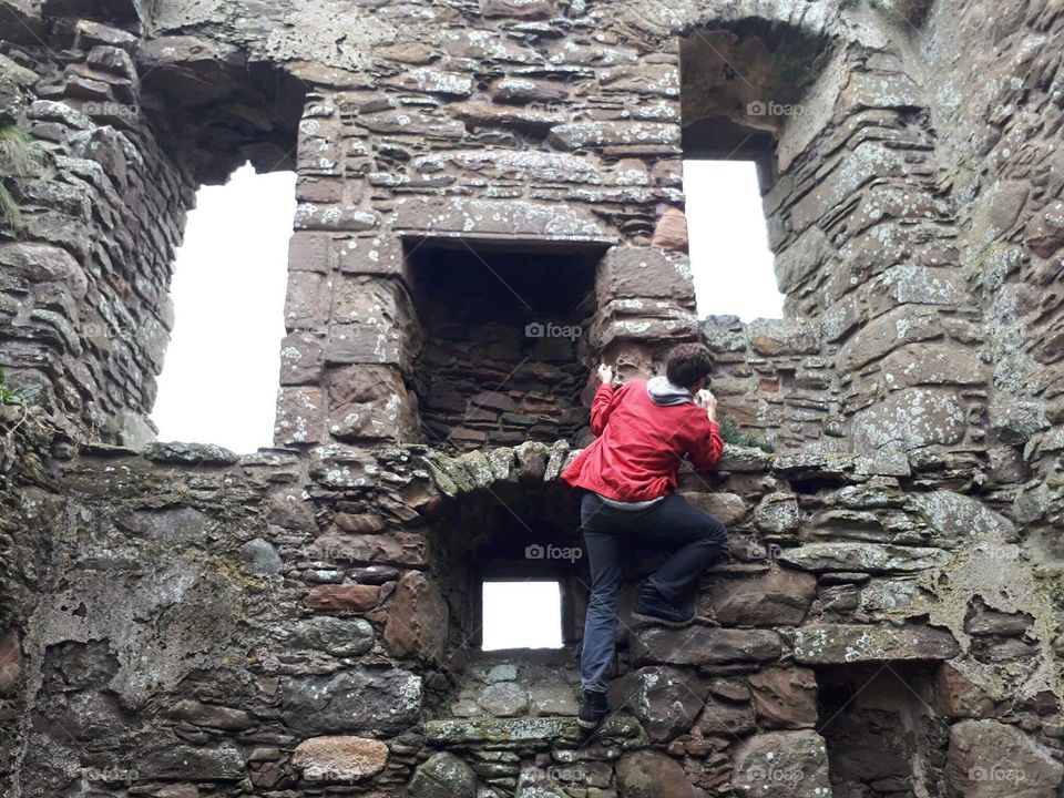 Teenager climbing a castle wall
