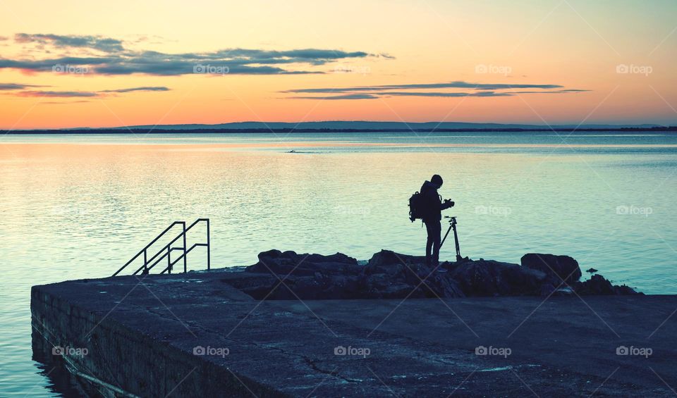 Photographer silhouette at sunrise, Salthill beach in Galway, Ireland