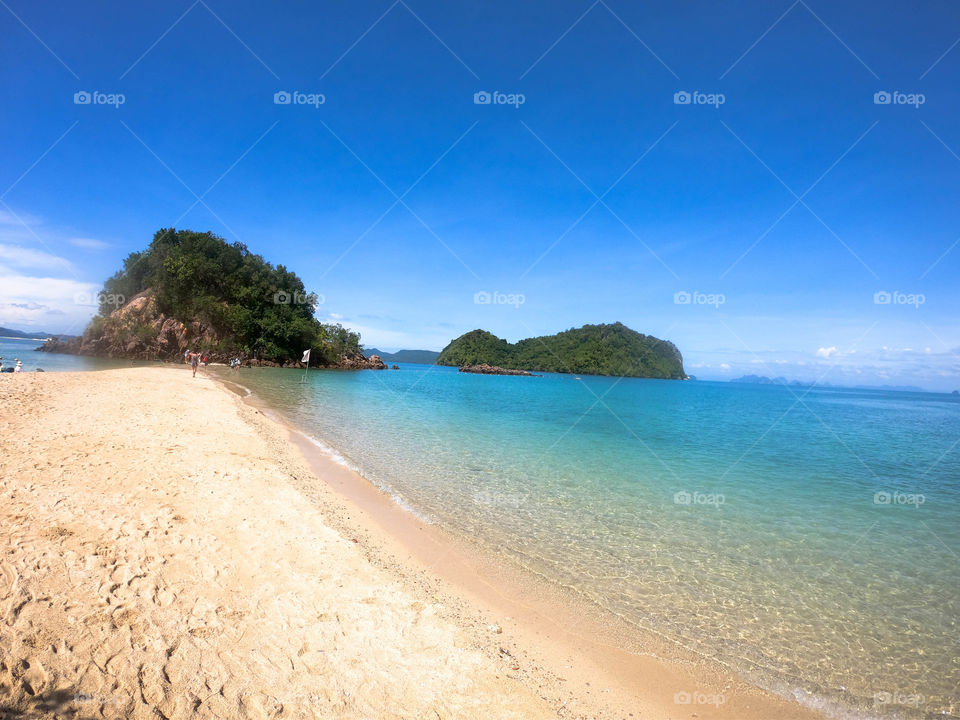 paradisíaca playa de Tailandia de aguas cristalinas y arenas blancas con paisajes rocosos y vegetación abundante