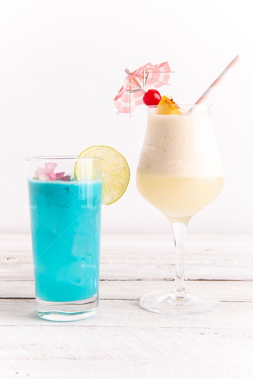 Closeup of two tropical, colorful cocktail beverages side by side on a table 