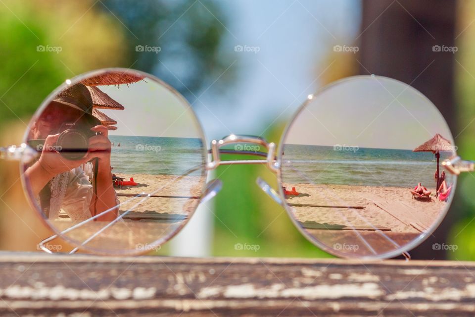 Reflection of the beach, photographer and summer on  mirrored sunglasses