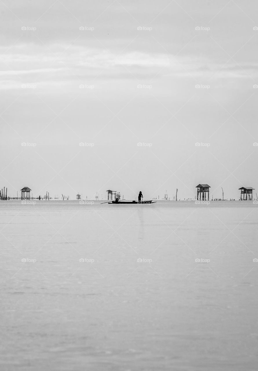 Silhouette of fisherman work on his boat in the cloudy day