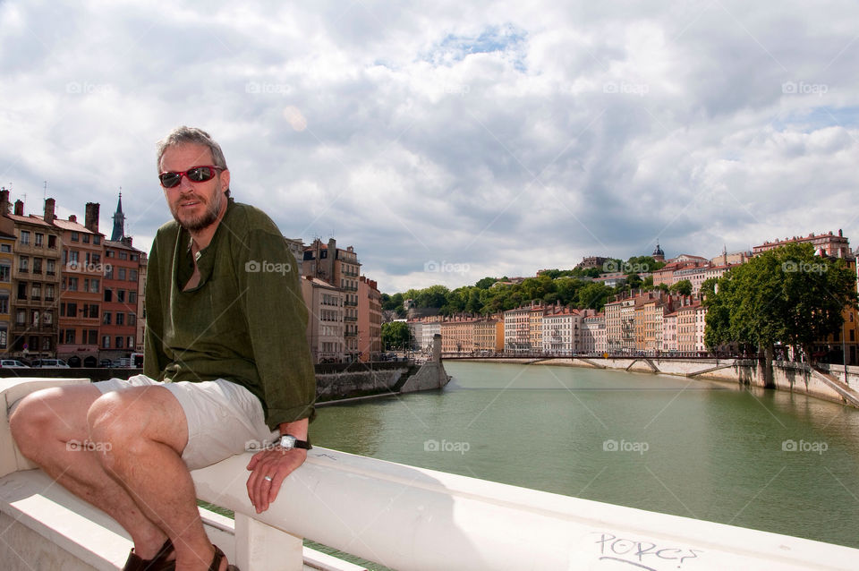 Man sits on a railing on a bridge over the Rhône River
