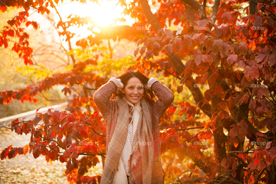 Young woman standing near autumn tree