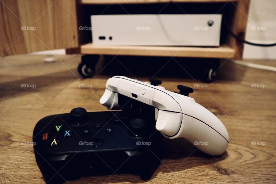 Xbox black and white controllers with the Xbox box at background 