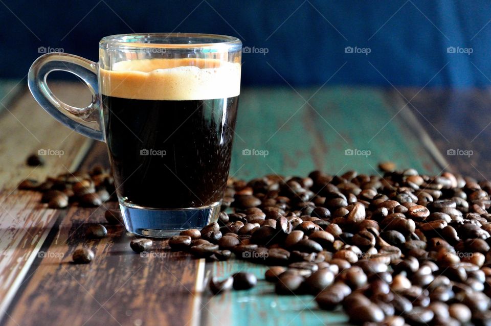 Black coffee with coffee beans on table