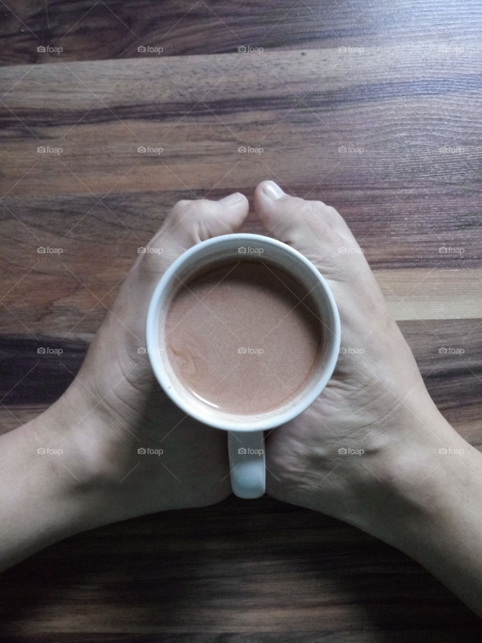 a pair of woman's feet holding a coffee cup in the morning against a wooden background