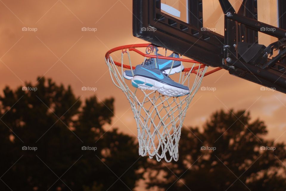 Nike basketball . Nike, INC shoes in a basketball hoop at sunset 