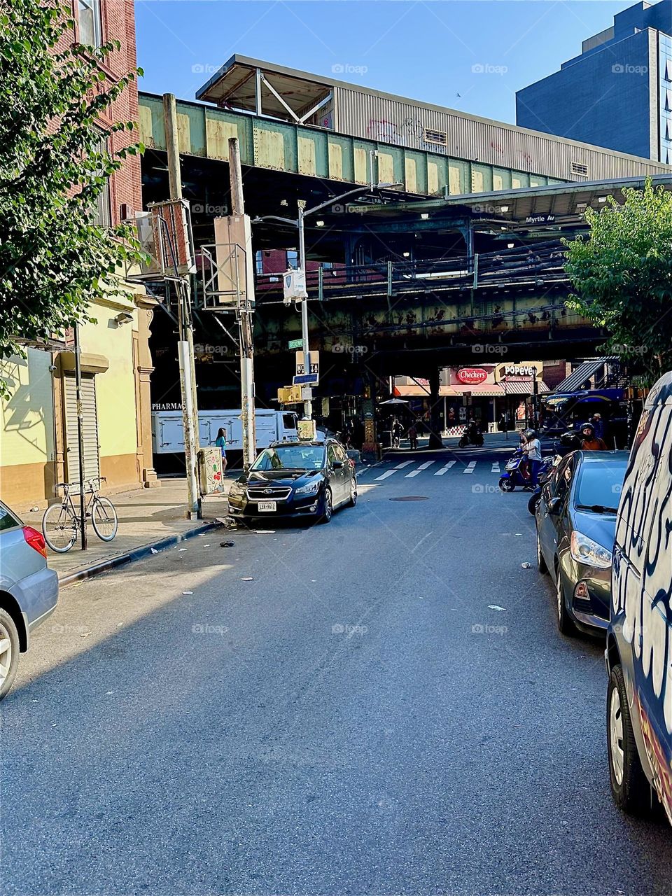 This is “Jefferson St” and “Broadway” in “Bushwick”, Brooklyn looking at the “Myrtle Ave” station “M” train overpass in the golden late afternoon sun. 2024. Hypnotic Productions