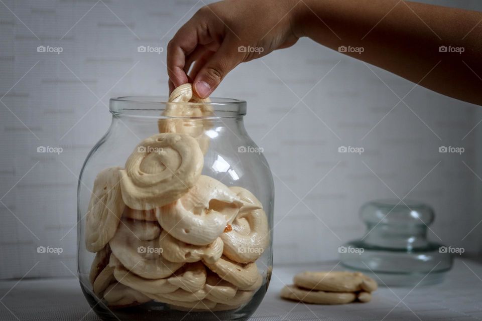 Child's hand is taking a cookie from a cookie jar