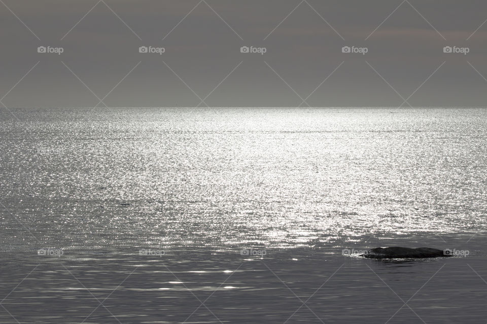 Sunlight on seascape and view of rock in water