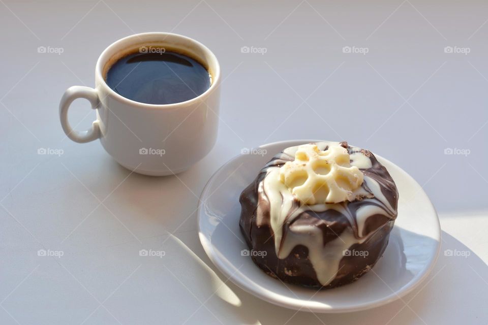 cup of coffee and cake in sunlight on a white background
