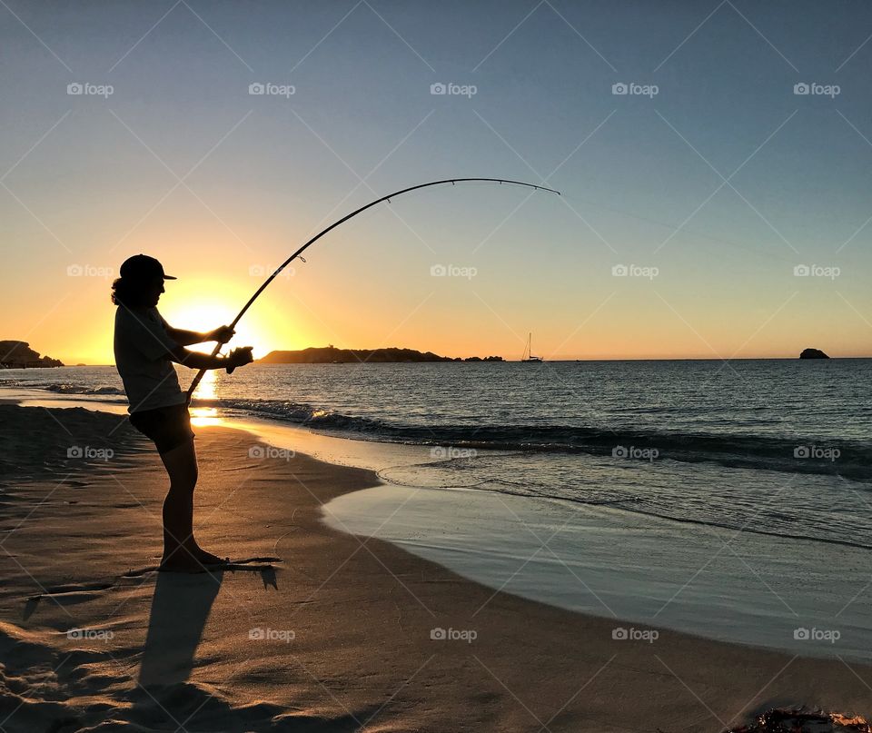 Catching a fish at the beach with an amazing sunset