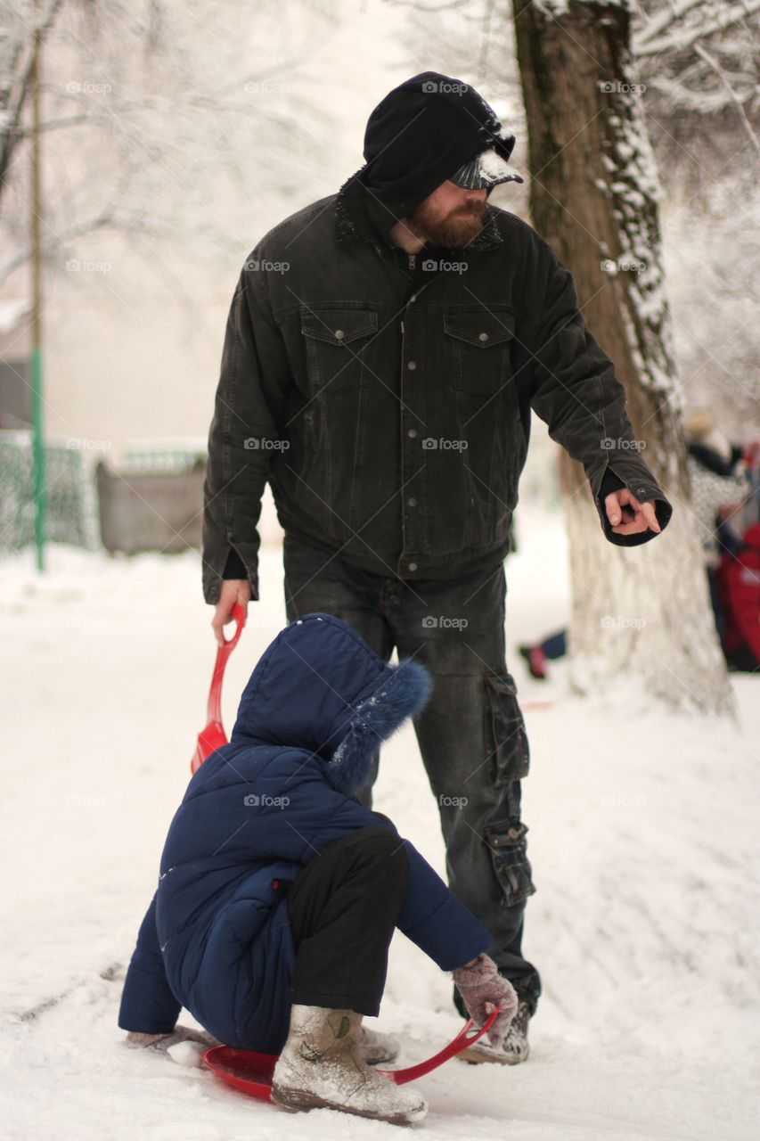 Dad shows daughter in which direction it is better to go down the hill in winter