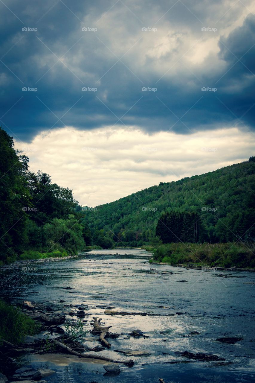 A moody portrait of the semois in vresse sur semois in the belgian ardennes. the cloudy sky really sets the dark and cold mood for this landscape.