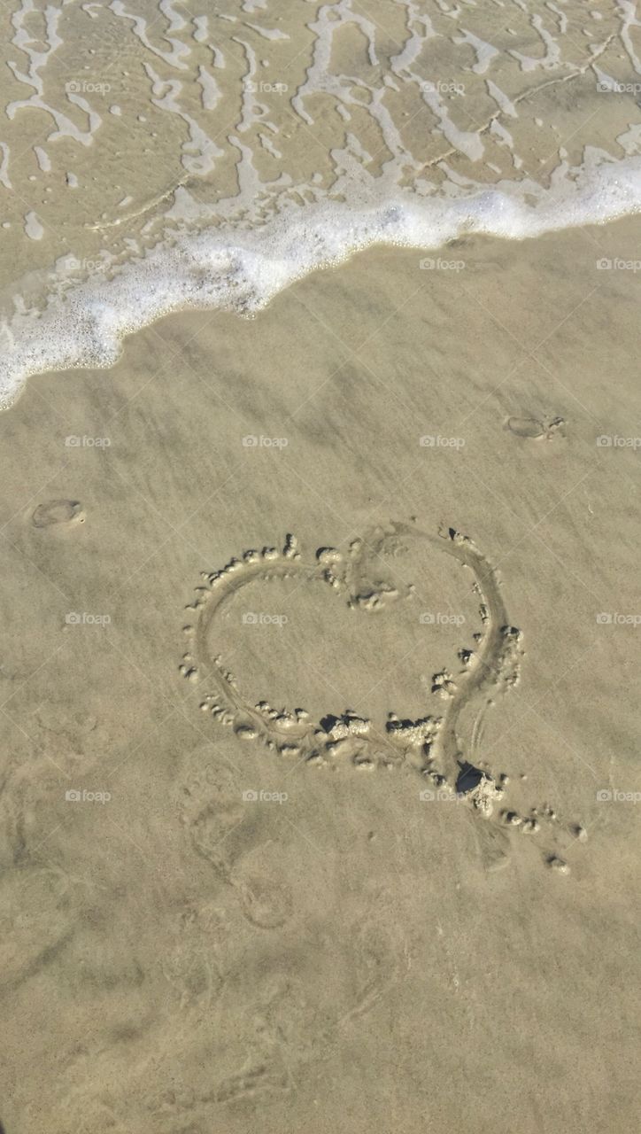 Love at the beach . A heart drawn in the sand 