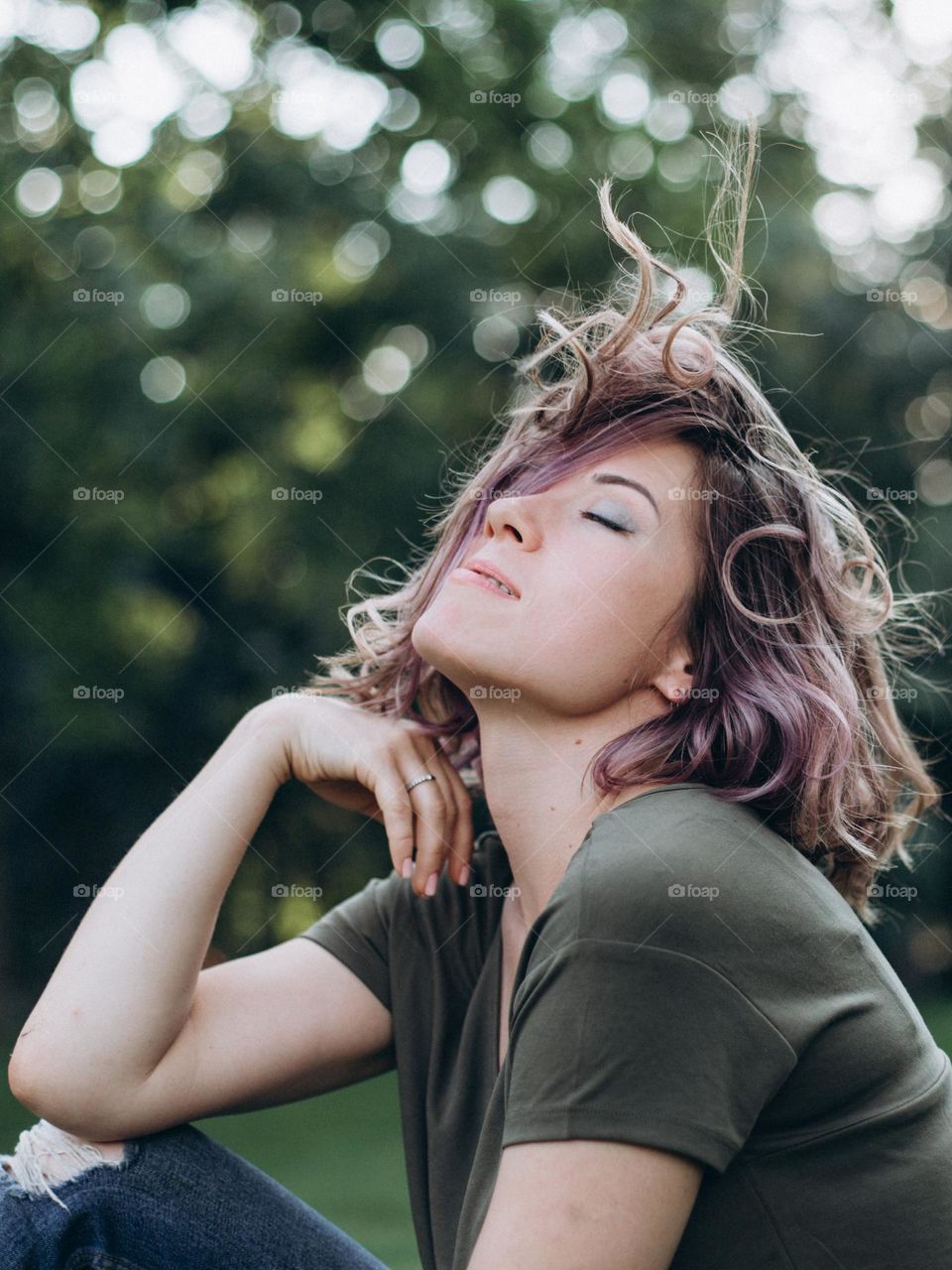 Happy girl on green clothes outside blow hair