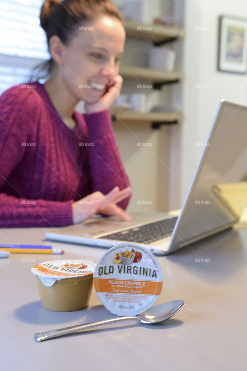Smiling Woman at her laptop with a Snack