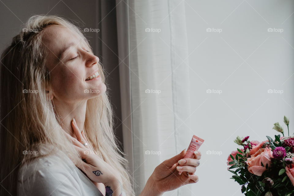 smiling woman using skin care product