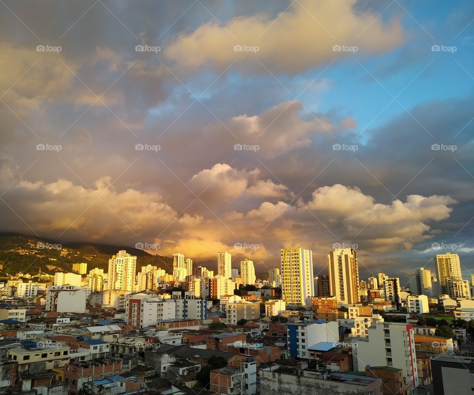 El sol del atardecer, da colores a las nubes y los edificios creando un hermoso paisaje.