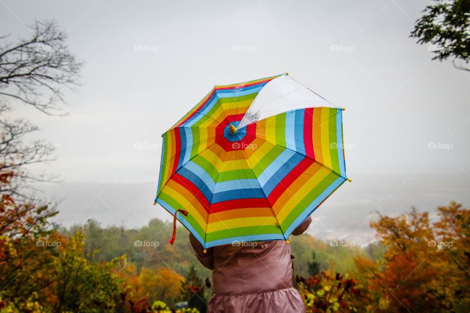 Child with rainbowy umbrella on a beautiful view point