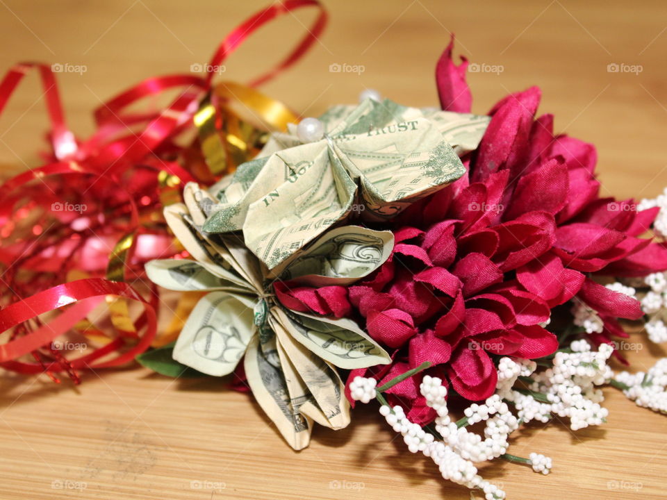 A beautifully decorated money flower with wine colored flower accents and gold ribbon