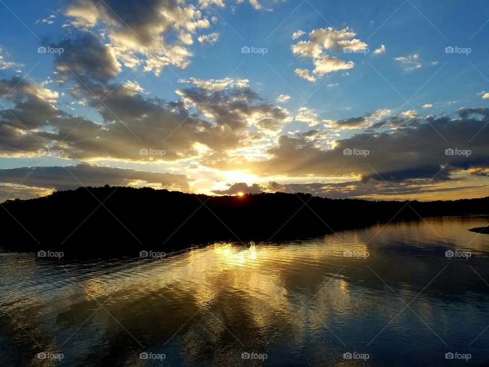 sun rays are all that is left as the sun sets behind the island.  reflections on the lake brighten the view.