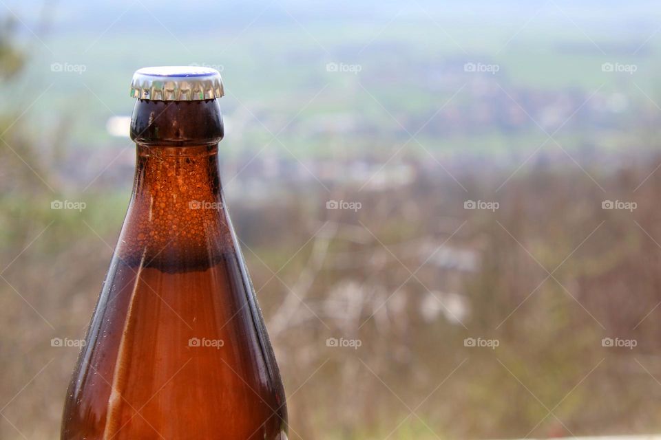 Close-up of a beer bottle with  scenic view in the background